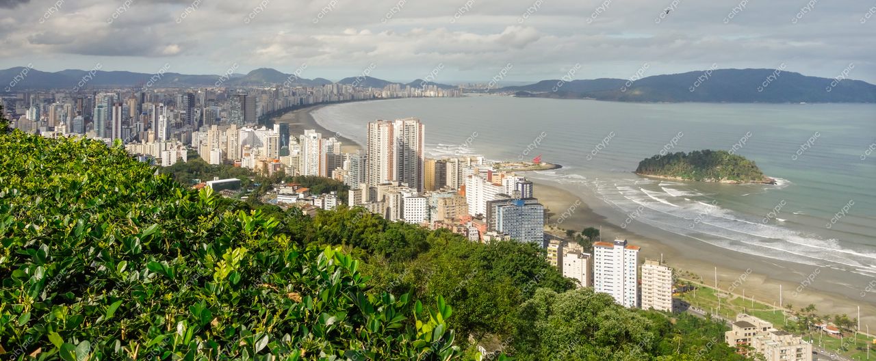 Santos, São Paulo, vista panorâmica da orla com arranha-céus, montanhas ao fundo e céu parcialmente nublado