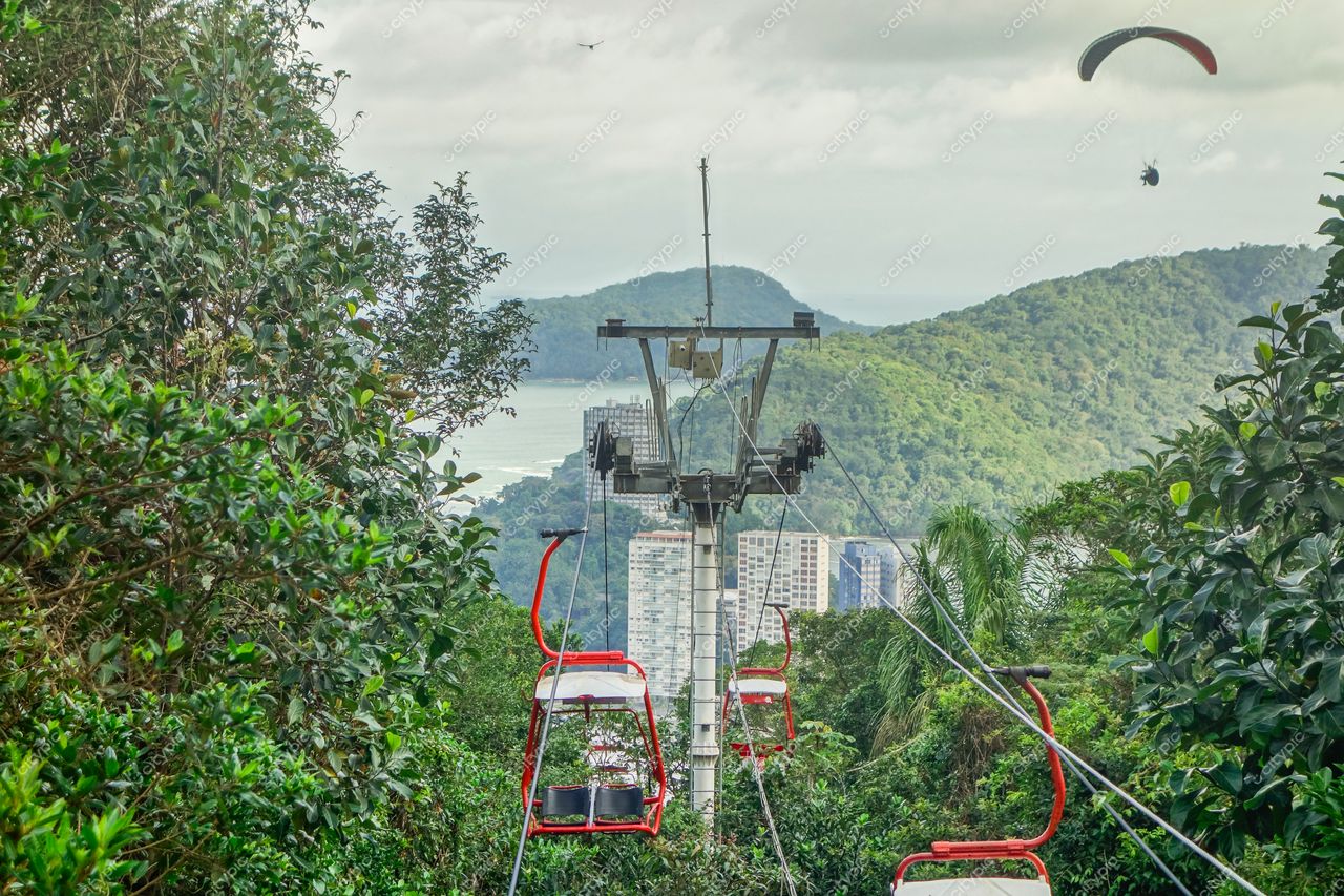 Santos, São Paulo teleférico vermelho em meio à vegetação densa com colinas verdes e litoral ao fundo em dia nublado