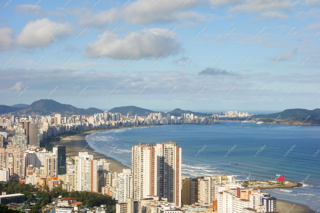 Santos, São Paulo, vista panorâmica da praia com prédios altos e montanhas ao fundo em dia claro