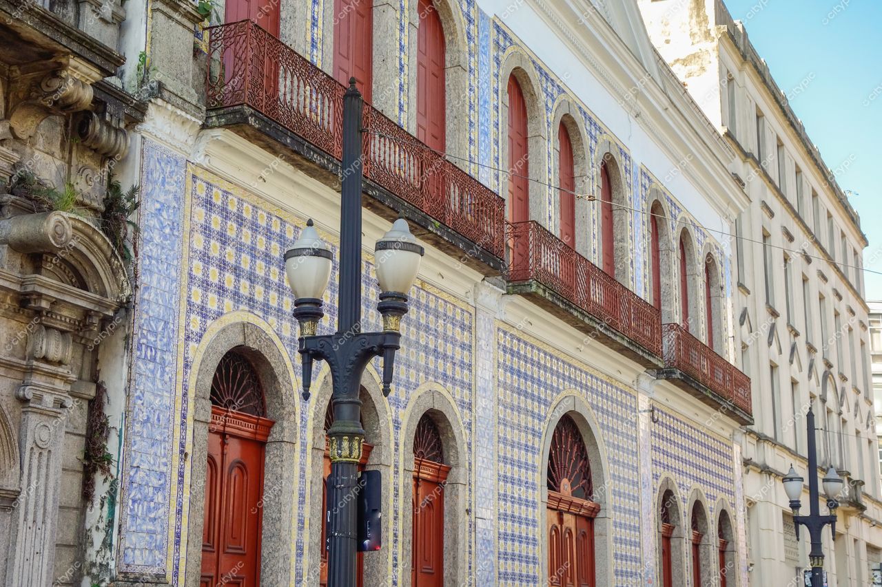 Santos, São Paulo, fachada com azulejaria azul e amarela em dia ensolarado com vegetação e postes de luz