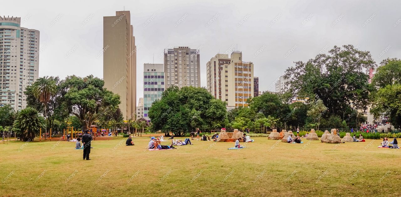 São Paulo, São Paulo, parque urbano com vegetação densa e prédios altos em dia nublado com pessoas relaxando