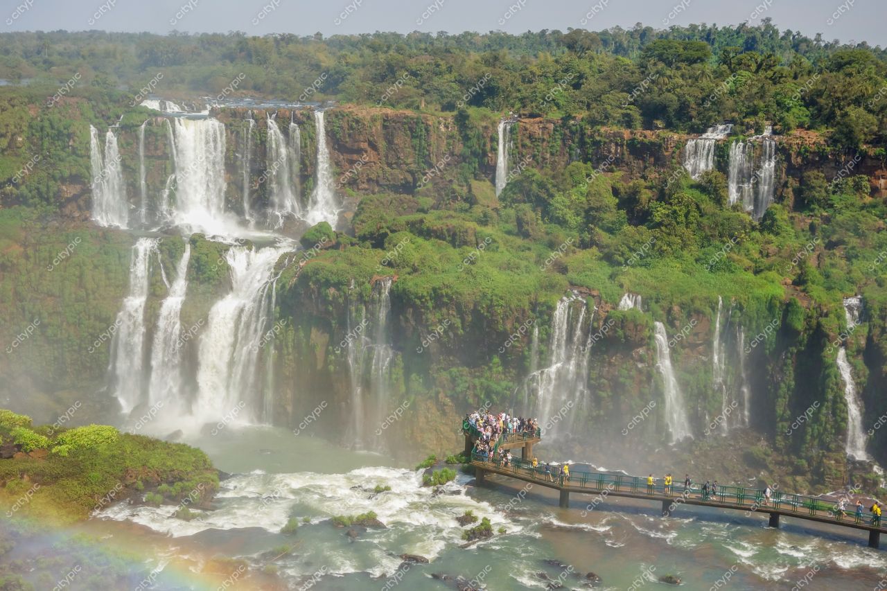 Cataratas do Iguaçu em Foz do Iguaçu com passarela de madeira e vegetação tropical sob céu claro e luz vibrante