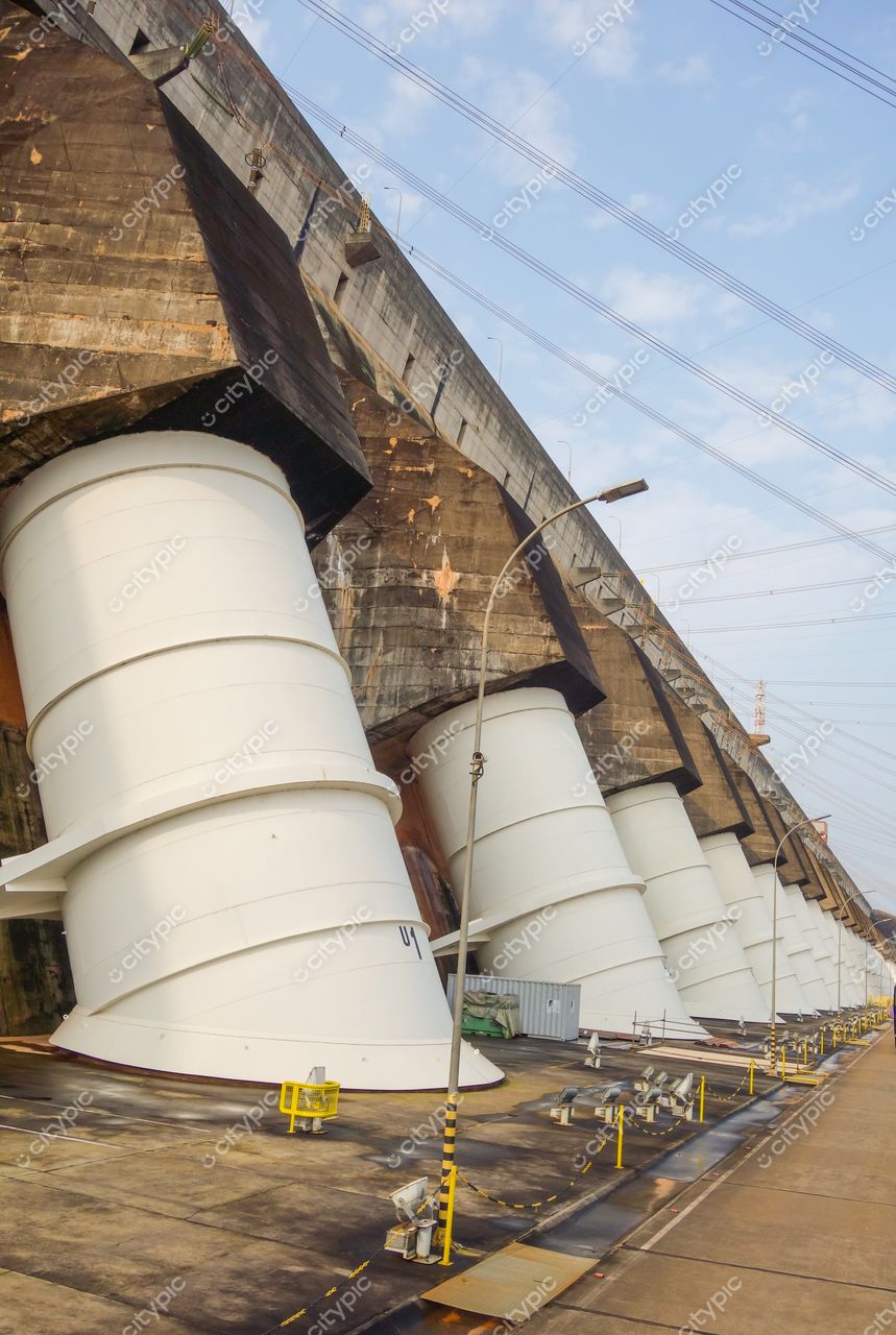 Barragem de Itaipu em Usina de Itaipu com turbinas brancas em primeiro plano e céu claro ao fundo
