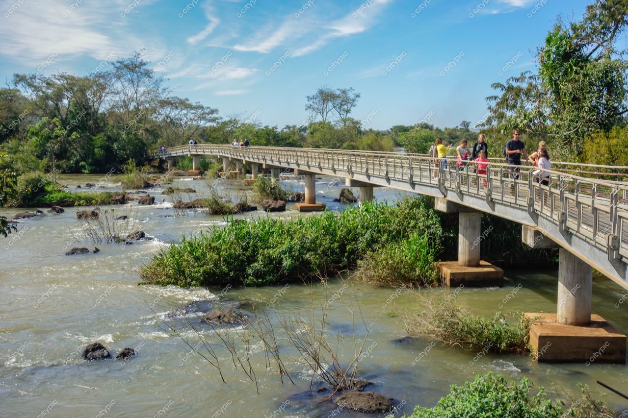 Cataratas do Iguaçu em Foz do Iguaçu com ponte de pedestres, vegetação densa e céu limpo em dia ensolarado