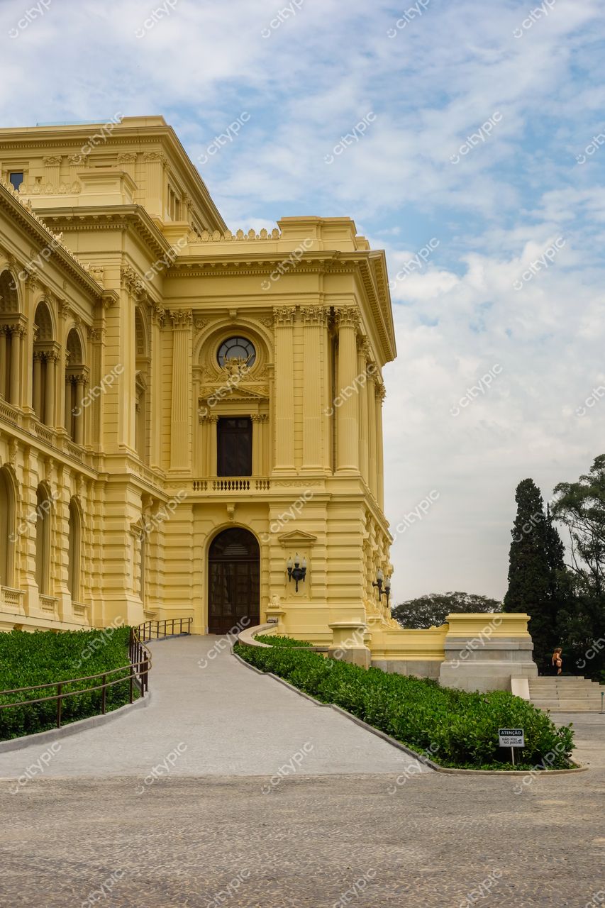 São Paulo, São Paulo, edifício histórico amarelo com rampa de acesso e vegetação em dia parcialmente nublado