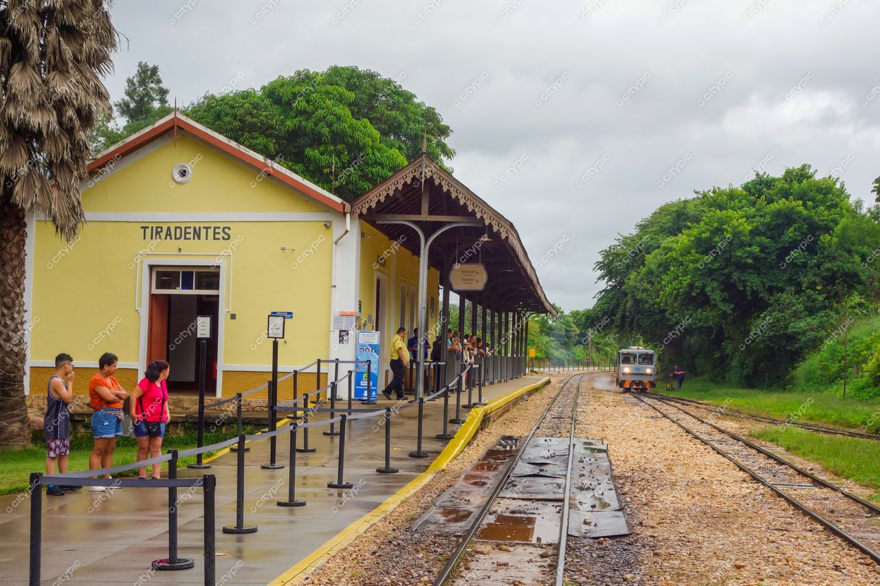 Tiradentes, Minas Gerais, estação de trem com arquitetura tradicional sob céu nublado e vegetação densa ao fundo