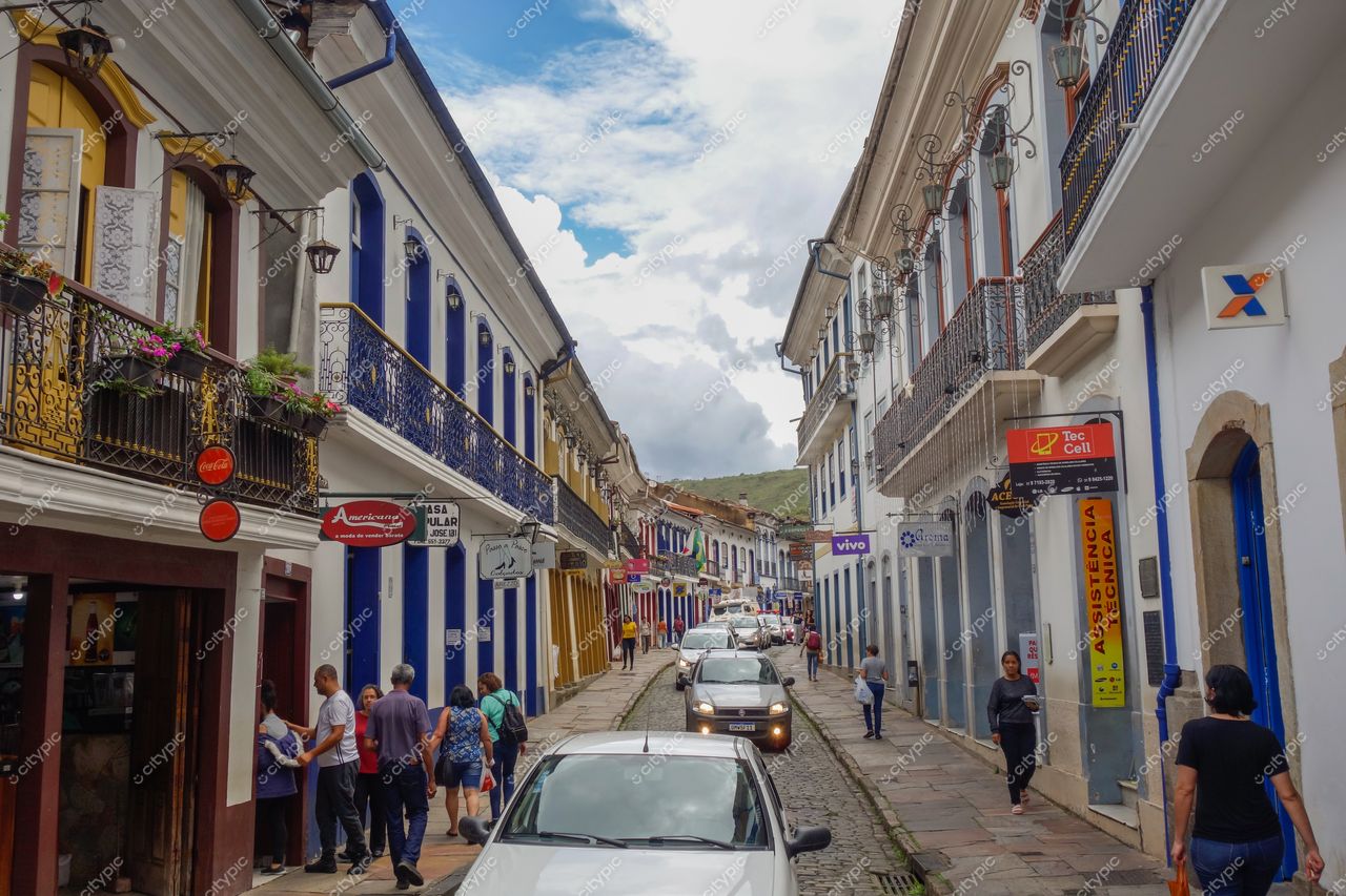 Ouro Preto, Minas Gerais, rua de paralelepípedos com edifícios coloniais coloridos em dia nublado e movimento local