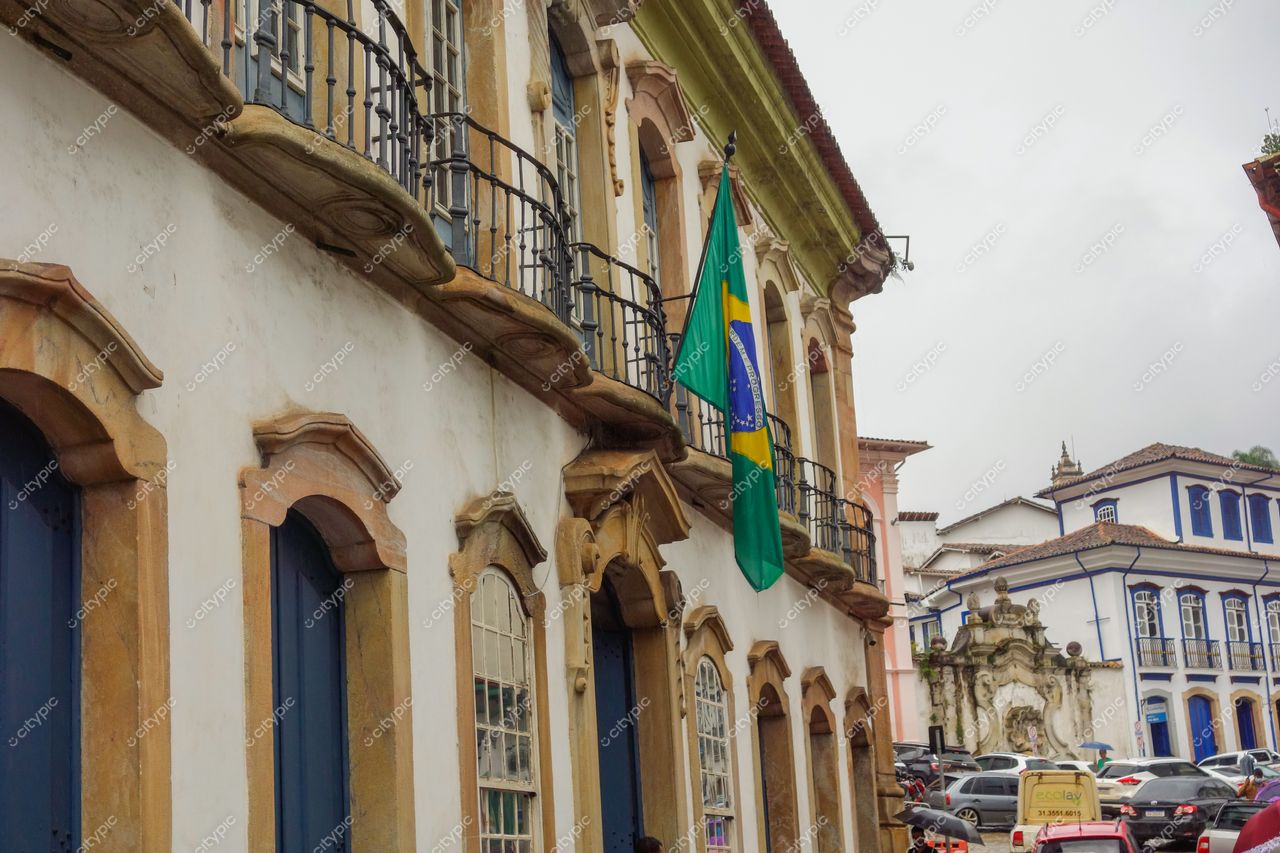 Ouro Preto, Minas Gerais, rua com arquitetura colonial e bandeira do Brasil em dia nublado e tráfego discreto