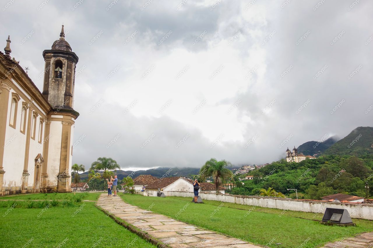 Ouro Preto, Minas Gerais com arquitetura colonial e pessoas caminhando em dia nublado entre colinas verdes e vegetação