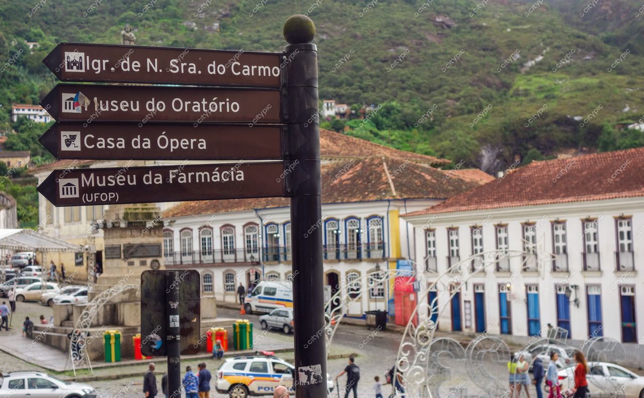 Ouro Preto, Minas Gerais com sinalização turística e arquitetura colonial em dia claro e leve movimento de pessoas e veículos