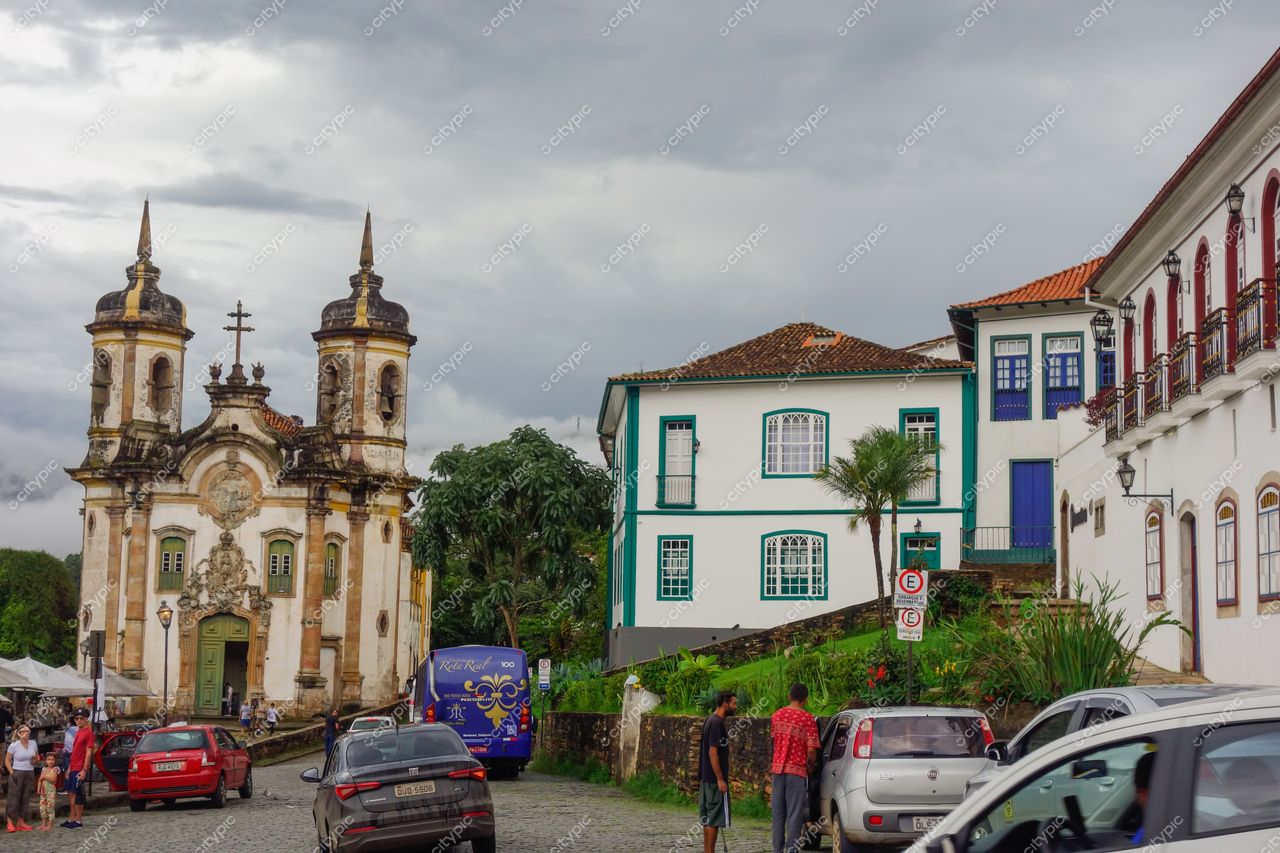 Ouro Preto, Minas Gerais, igreja colonial com torres sob céu nublado e casas brancas em rua movimentada
