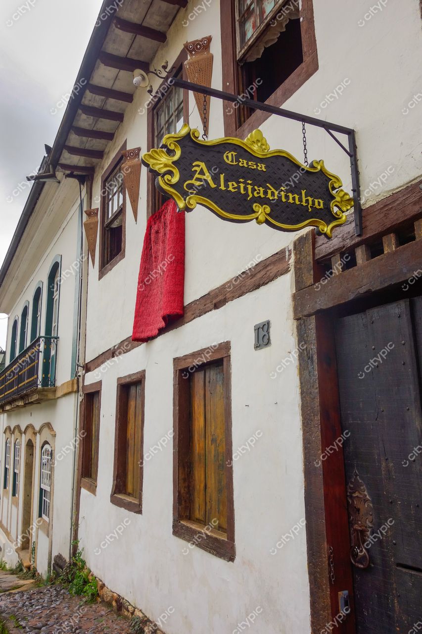 Ouro Preto, Minas Gerais, fachada da Casa Aleijadinho com letreiro e toalha vermelha em dia nublado
