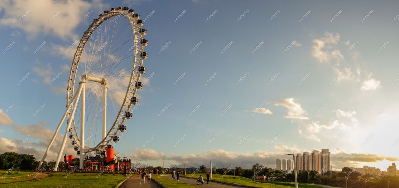São Paulo, São Paulo, roda-gigante iluminada pelo pôr do sol com vegetação ao redor e pessoas caminhando