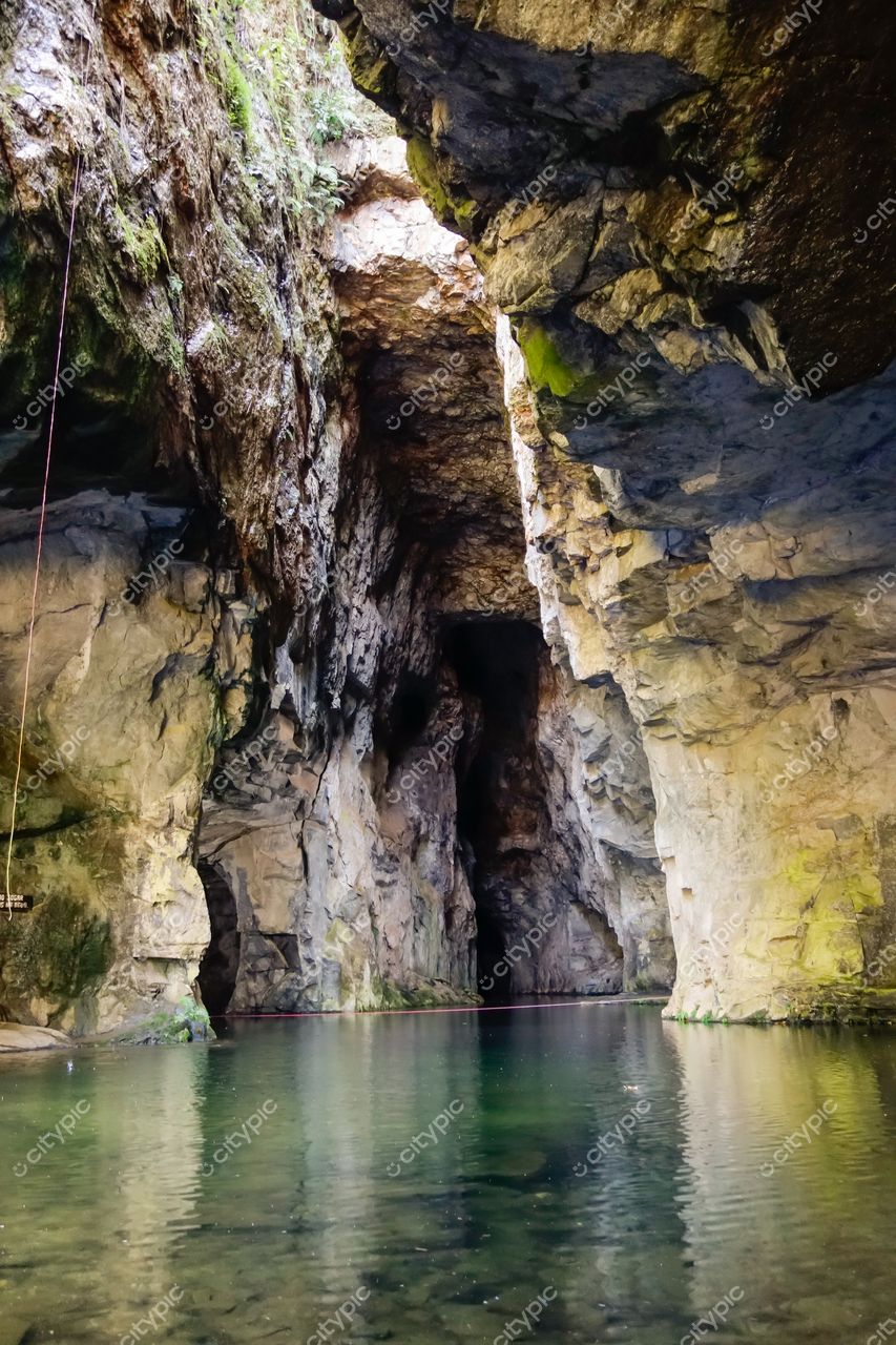 Socorro, São Paulo, caverna com paredes de rocha exposta e vegetação esparsa refletindo luz natural na água calma