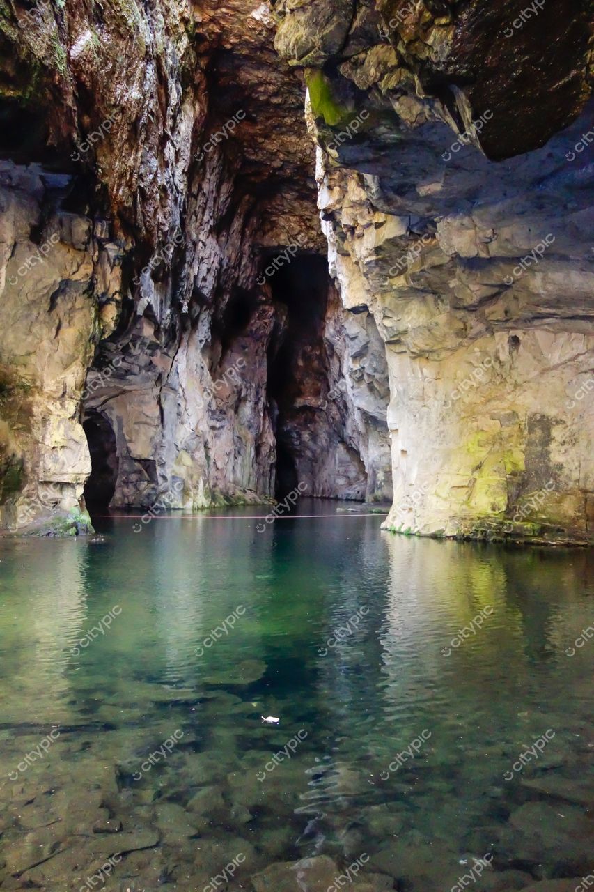 Socorro, São Paulo caverna com água tranquila refletindo rochas cinzas e verdes em iluminação natural diurna