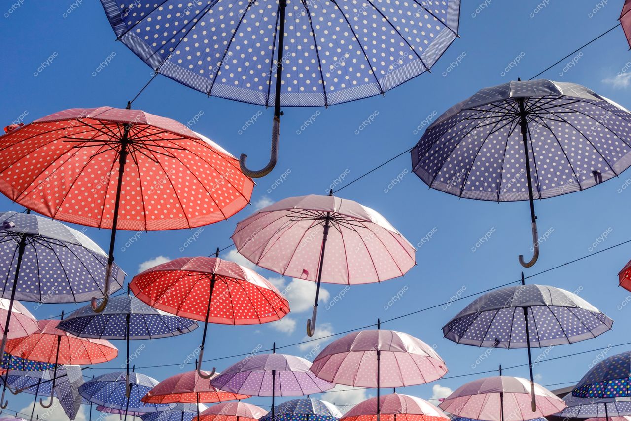 Socorro, São Paulo, céu azul claro com guarda-chuvas coloridos em tons de rosa e roxo suspensos por fios
