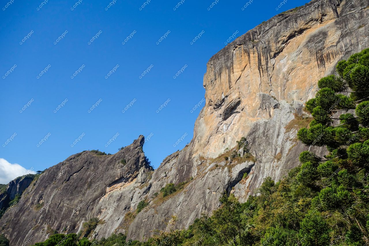São Bento do Sapucaí, São Paulo, formações rochosas sob céu azul com vegetação densa e iluminação diurna detalhada
