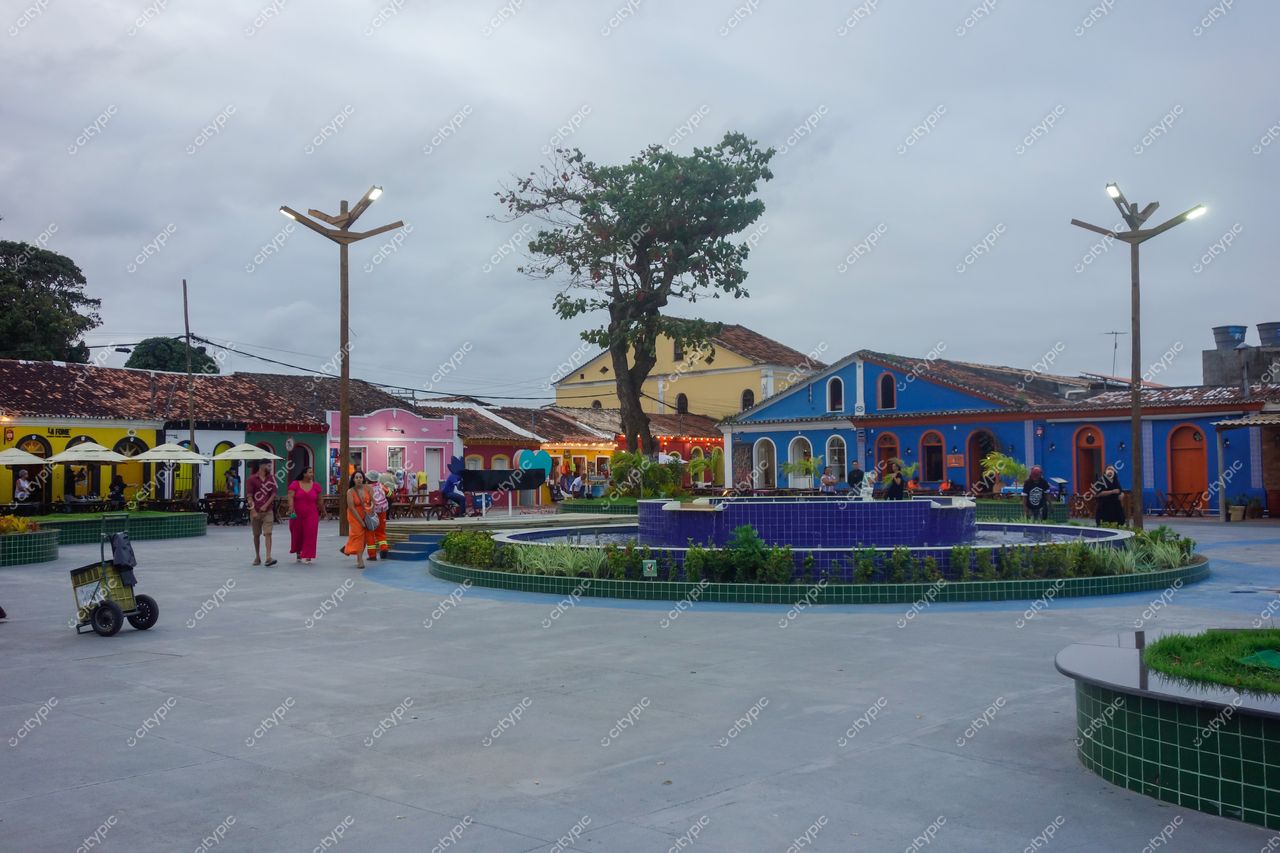 Passarela do Descobrimento em Porto Seguro com fonte circular e fachadas coloridas em dia nublado e tranquilo