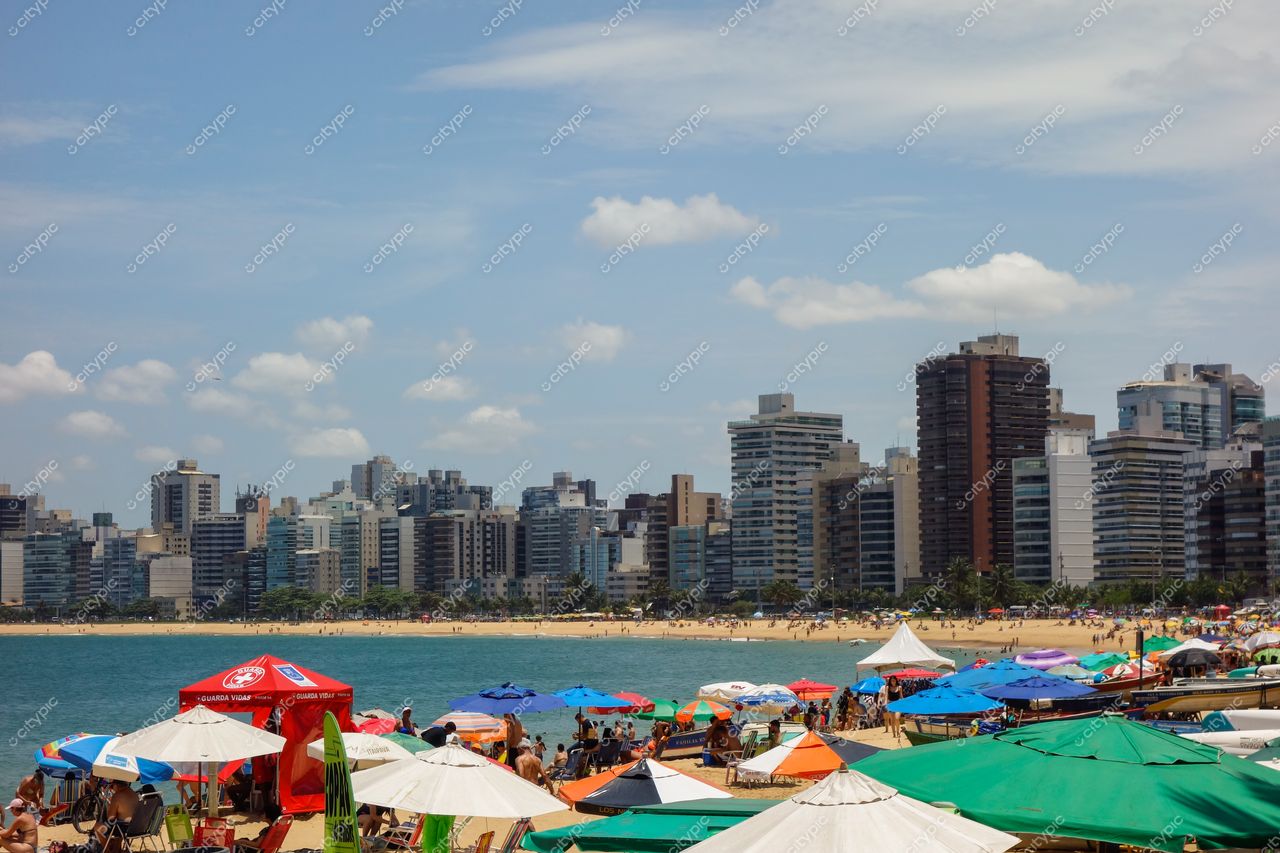 Vila Velha, Espírito Santo com vista panorâmica da praia em dia ensolarado e orla cheia de banhistas e guarda-sóis