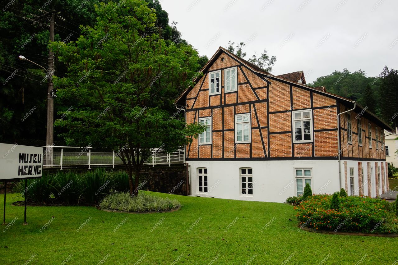 Museu Hering em Blumenau com fachada de tijolos e madeira sob céu nublado e gramado bem cuidado ao redor
