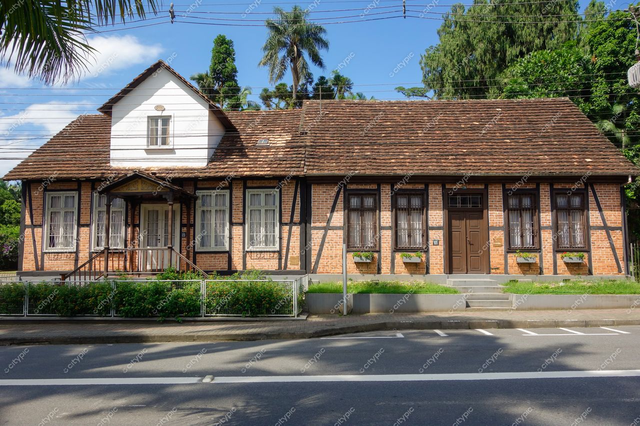 Blumenau, Santa Catarina casa de tijolo exposto e madeira em dia ensolarado com vegetação e rua pavimentada