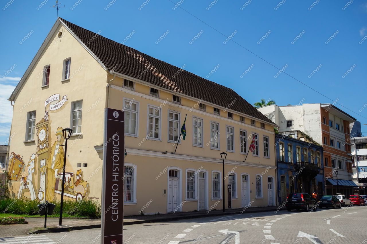 Centro Histórico de Blumenau em Blumenau com edifício amarelo, mural temático e vegetação em dia ensolarado