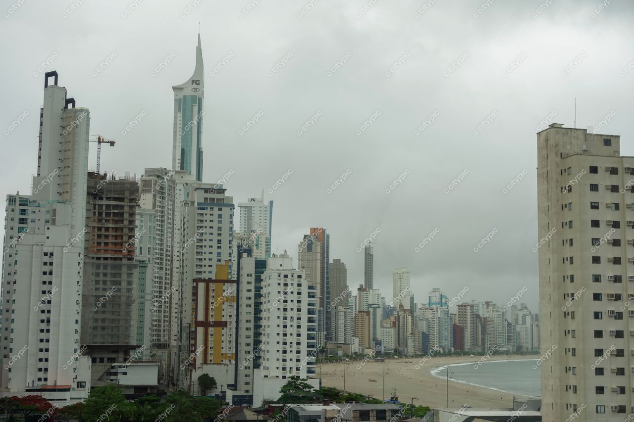 Balneário Camboriú, Santa Catarina com skyline de arranha-céus sob céu nublado e vegetação nas bases dos prédios