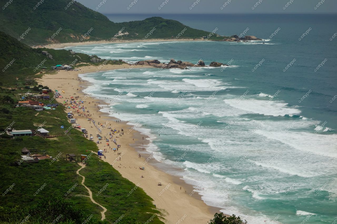 Florianópolis, Santa Catarina, vista panorâmica da Praia do Santinho com vegetação, quiosques e pessoas na areia
