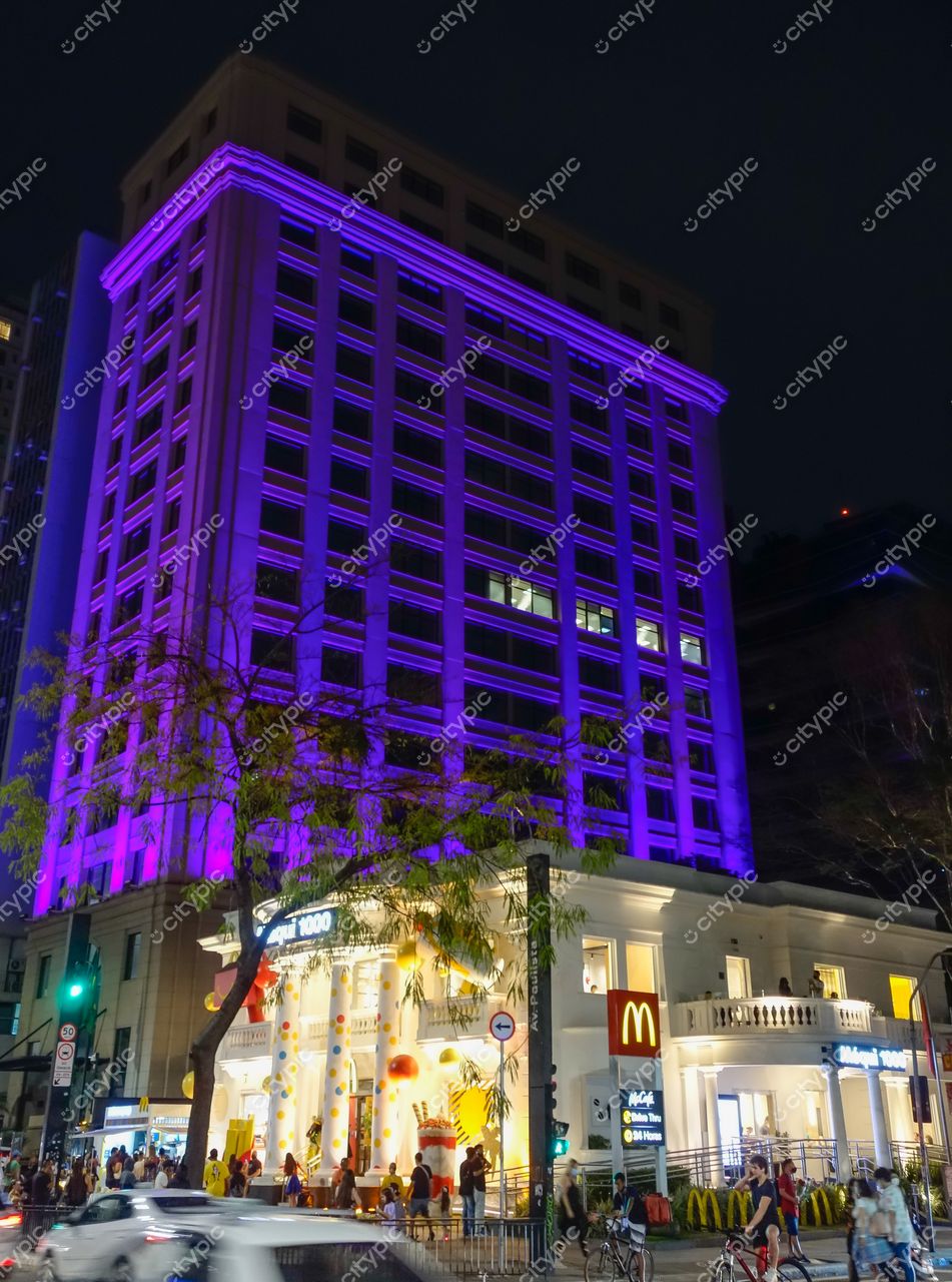 São Paulo, São Paulo, edifício de esquina iluminado por luzes roxas à noite com McDonald’s e tráfego intenso
