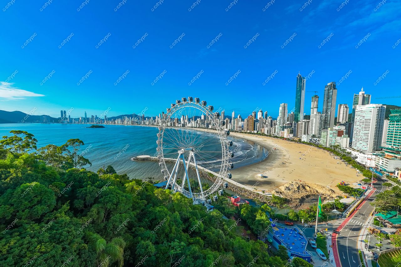 Balneário Camboriú, Santa Catarina com roda-gigante à beira-mar e arranha-céus sob céu azul claro e vegetação densa