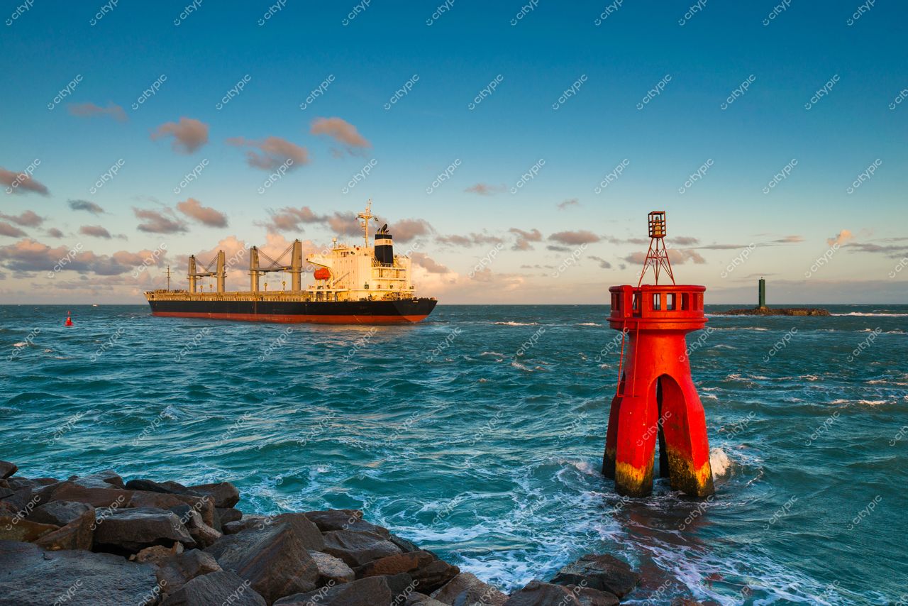 Natal, Rio Grande do Norte, farol vermelho em primeiro plano com navio cargueiro e enseada ao entardecer