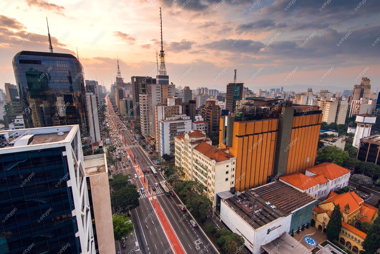 São Paulo, São Paulo, vista aérea ao crepúsculo com arranha-céus variados e vegetação em meio ao tráfego moderado