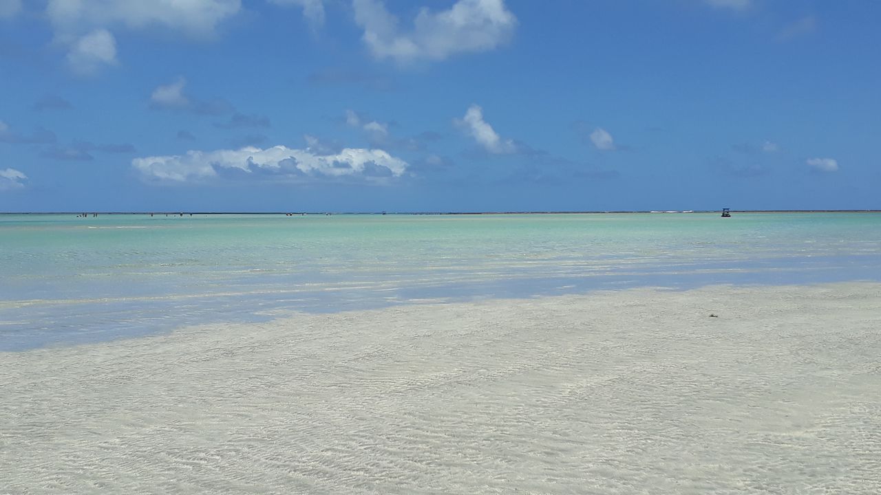 Maragogi, Alagoas vista da Praia com areia clara e mar calmo em dia ensolarado com arrecifes ao fundo