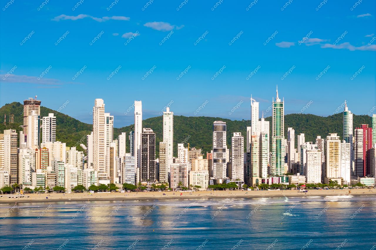 Balneário Camboriú, Santa Catarina, orla com arranha-céus refletindo na água e colinas verdes ao fundo
