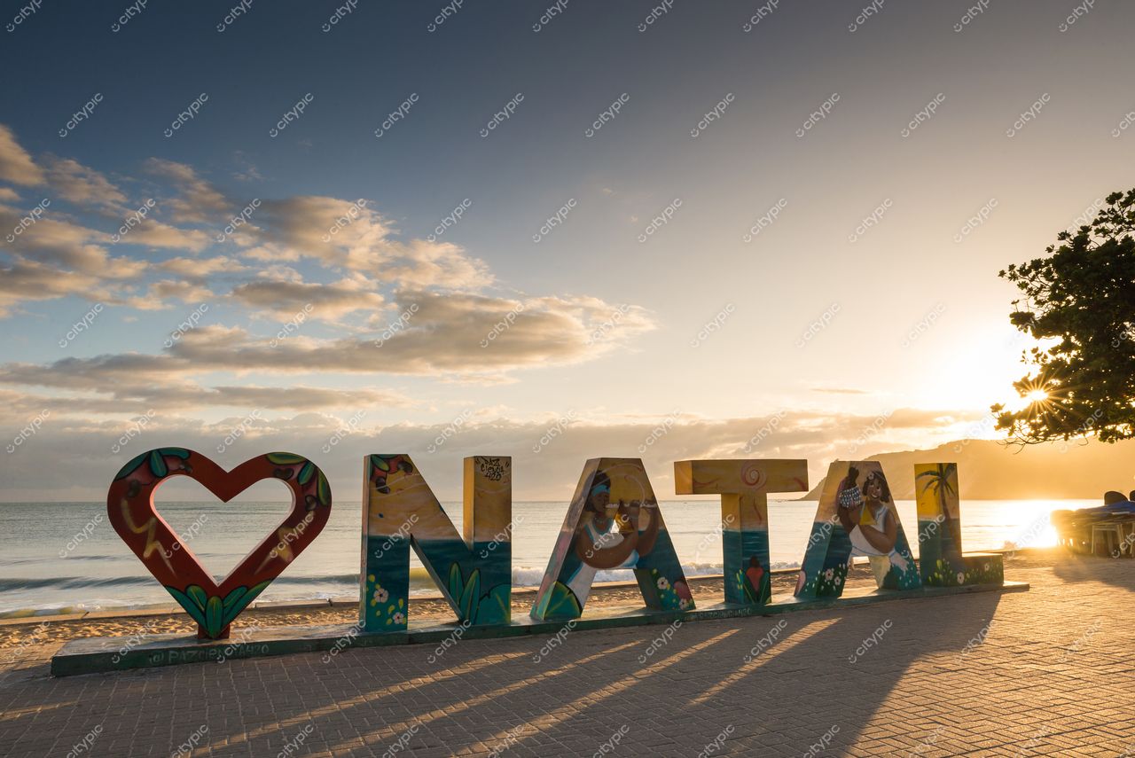 Natal, Rio Grande do Norte, letreiro “I ❤️ NATAL” ao amanhecer com ondas suaves e vegetação tropical ao fundo
