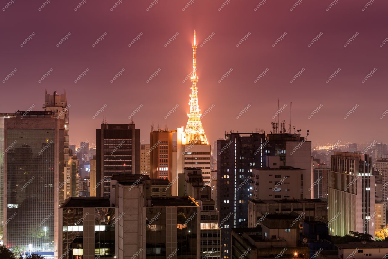 São Paulo, São Paulo, Edifício Altino Arantes iluminado à noite com céu roxo e arranha-céus ao fundo