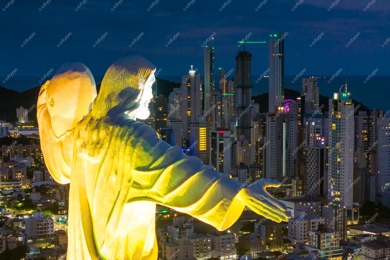 Balneário Camboriú, Santa Catarina, estátua de Cristo Luz iluminada à noite com arranha-céus e mar ao fundo