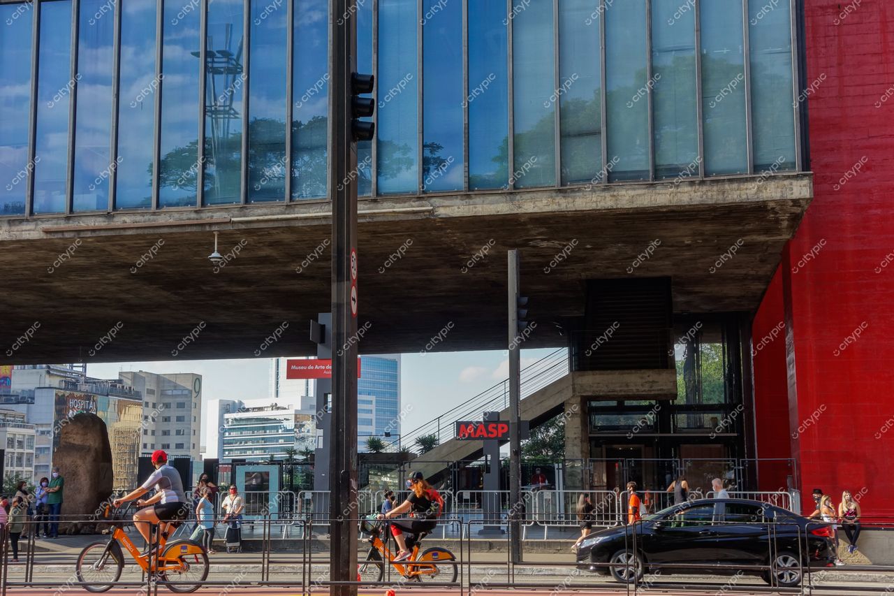MASP – Museu de Arte de São Paulo em dia ensolarado com bicicletas laranja e vegetação ao fundo na cidade movimentada