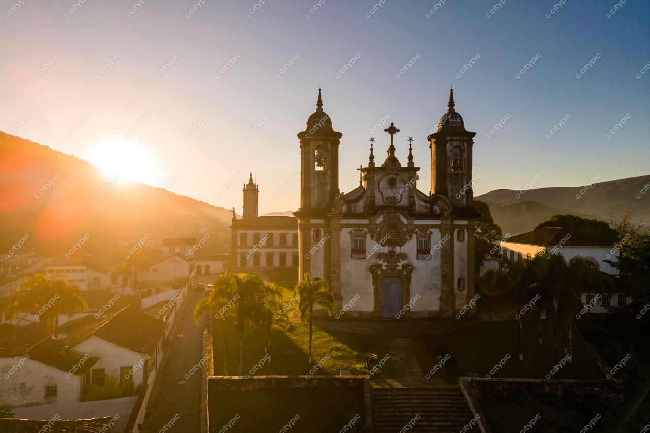 Ouro Preto, Minas Gerais ao amanhecer com luz suave destacando a igreja colonial e colinas ao fundo