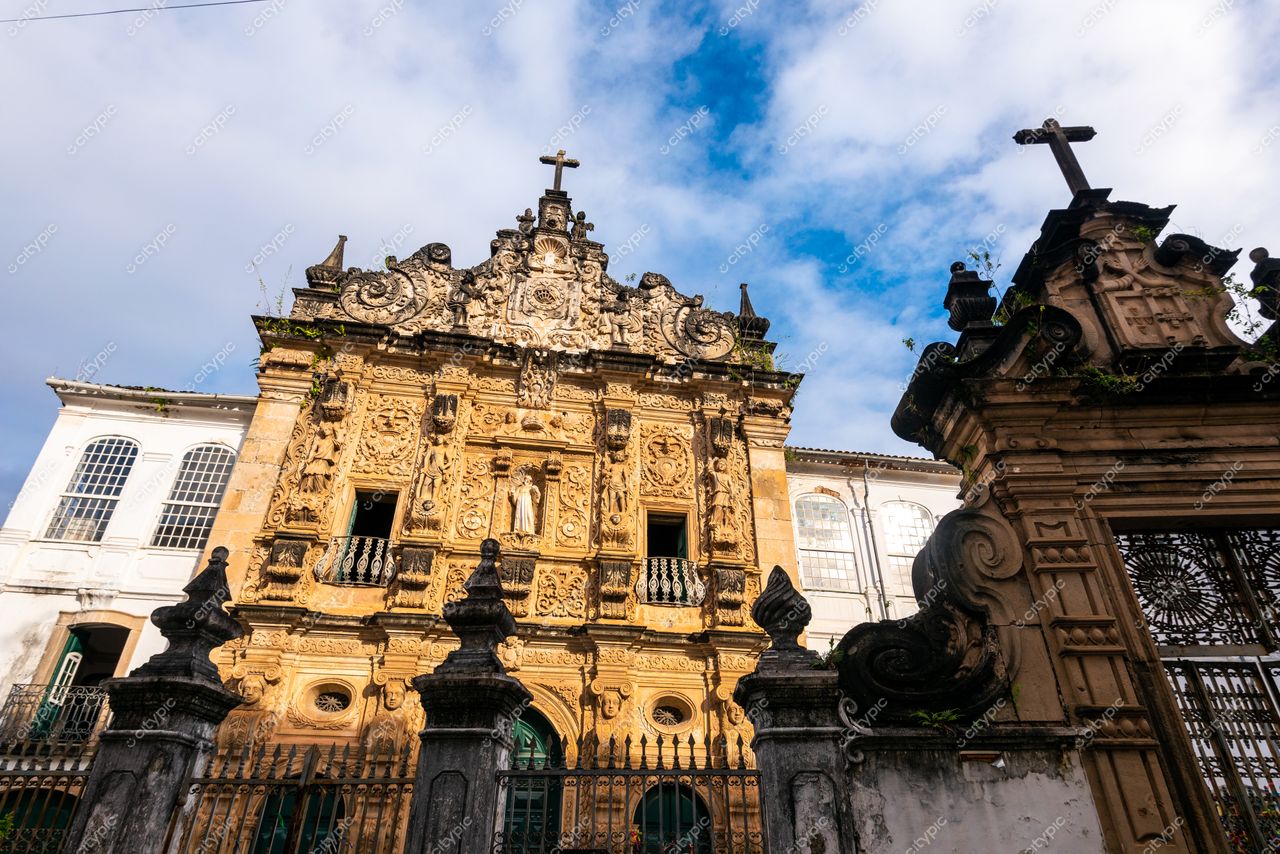 Salvador, Bahia, fachada barroca de edifício histórico com ornamentos em cores quentes sob céu azul parcialmente nublado