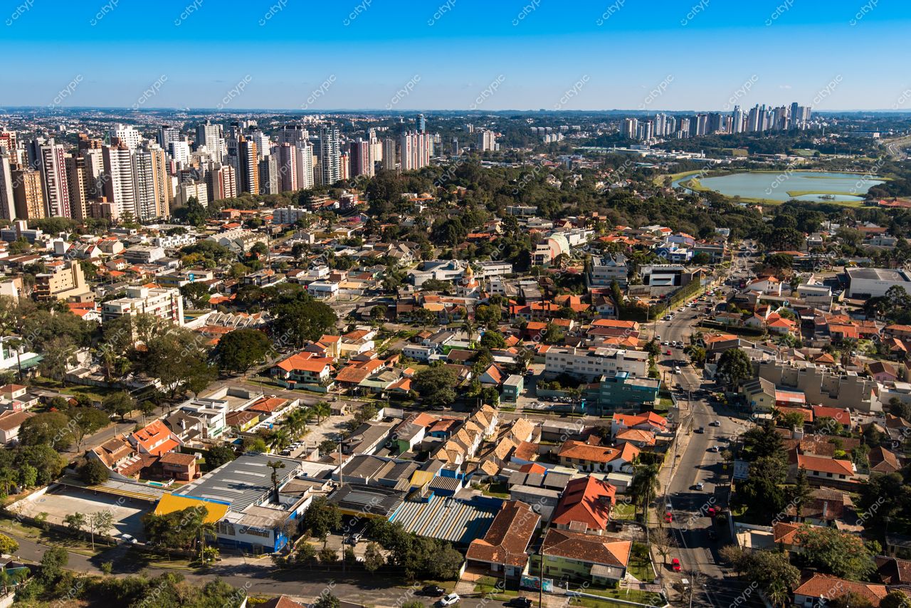 Curitiba, Paraná vista panorâmica com prédios altos ao fundo e bairro residencial em dia claro e vegetação abundante