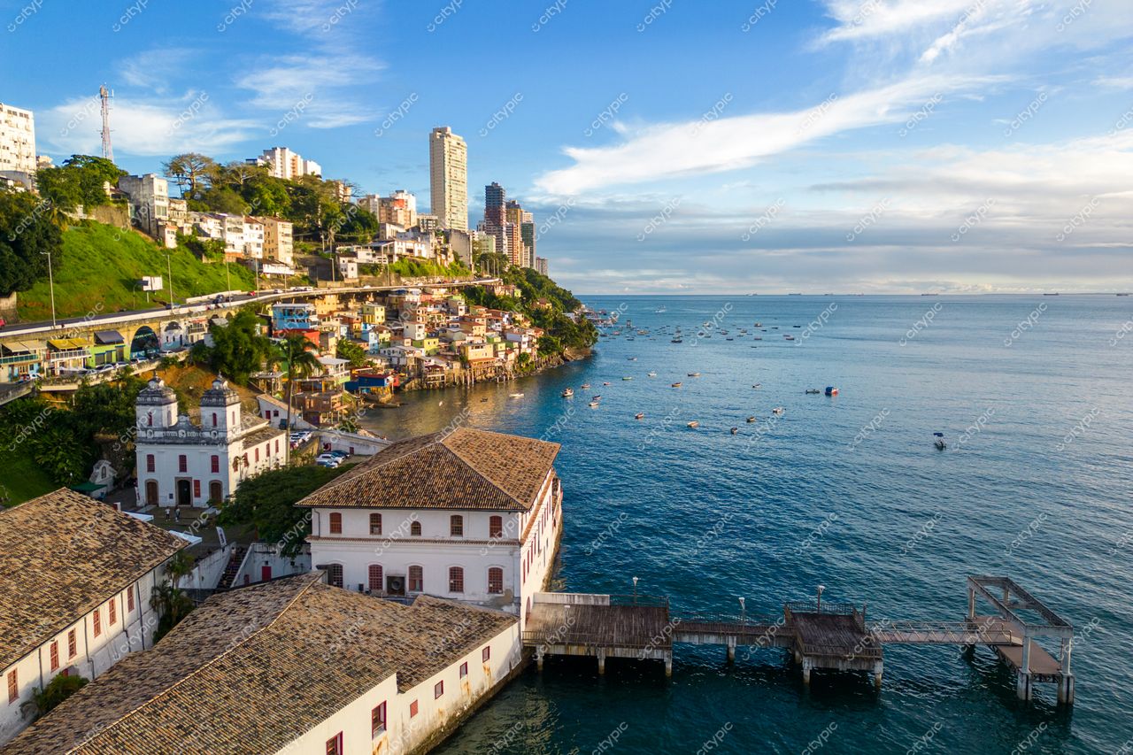 Salvador, Bahia com arquitetura colonial e moderna ao amanhecer, píer de madeira e vegetação contrastante na costa