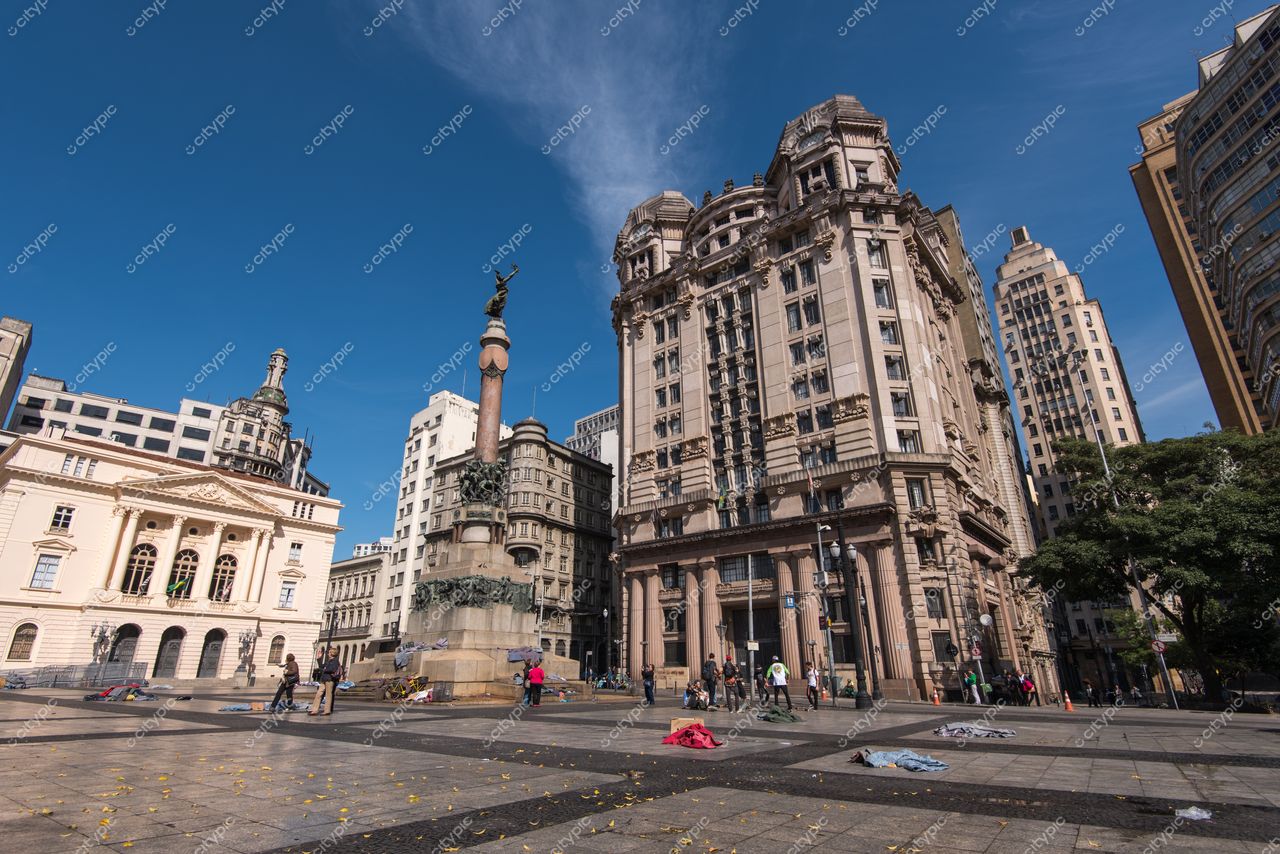 São Paulo, São Paulo, vista da Praça da Sé com céu azul e monumento cercado por edifícios históricos e vegetação