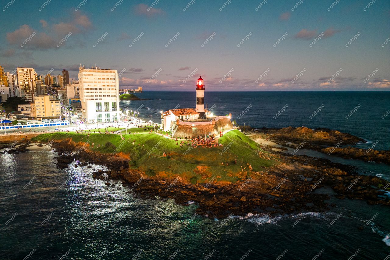 Salvador, Bahia, Farol da Barra ao entardecer com iluminação artificial e vegetação esparsa na costa urbana