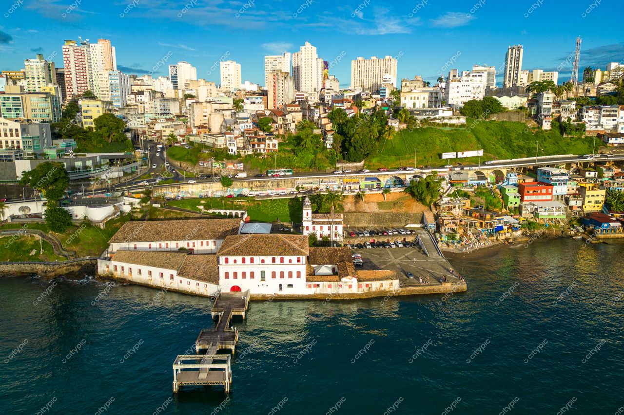 Salvador, Bahia vista aérea com edifício histórico à beira-mar, contrastando mar azul e áreas verdes urbanas