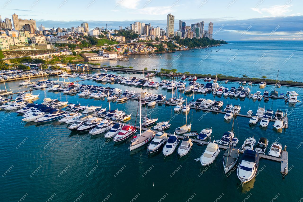 Salvador, Bahia, marina com iates ancorados em águas calmas ao pôr do sol e edifícios altos ao fundo