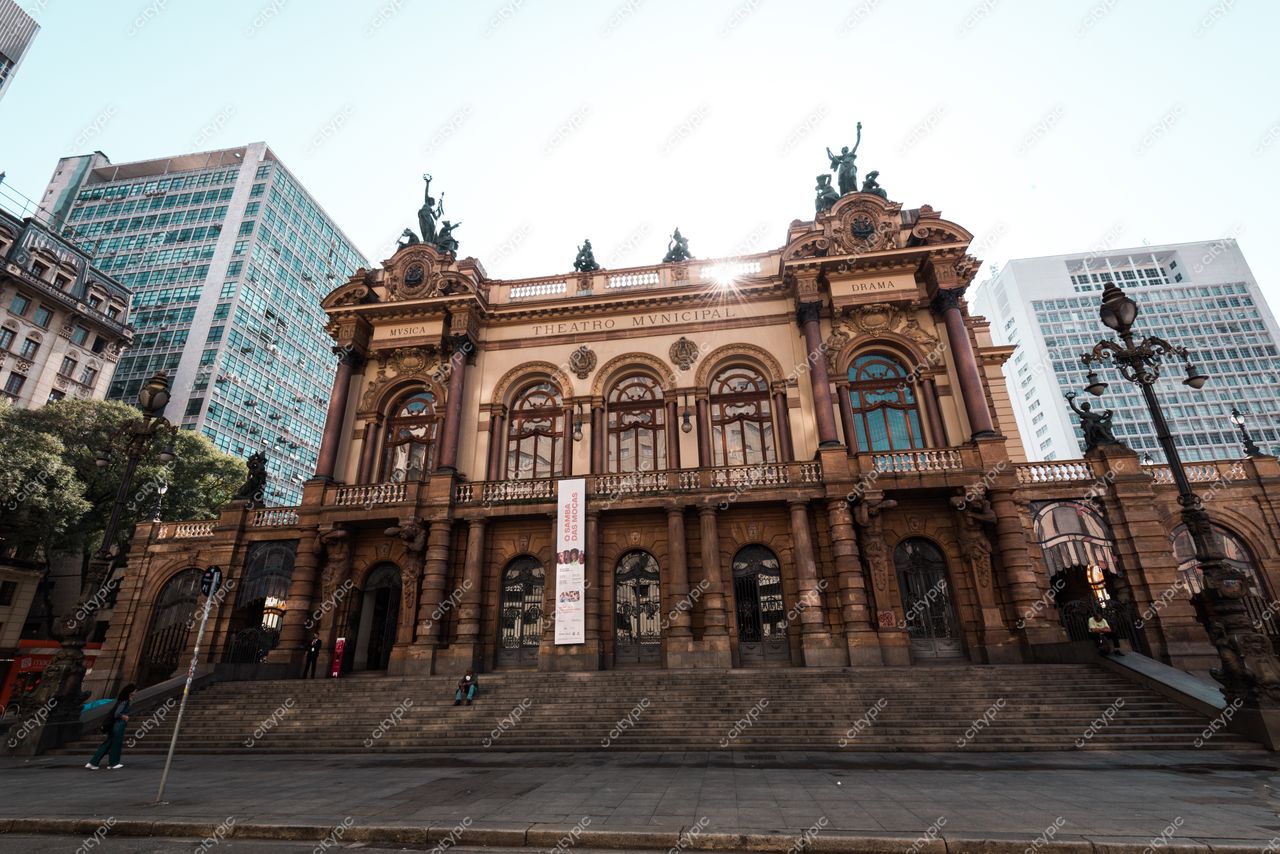 São Paulo, São Paulo, Teatro Municipal em dia ensolarado com fachada ornamentada e vegetação ao redor contrastando com edifícios modernos
