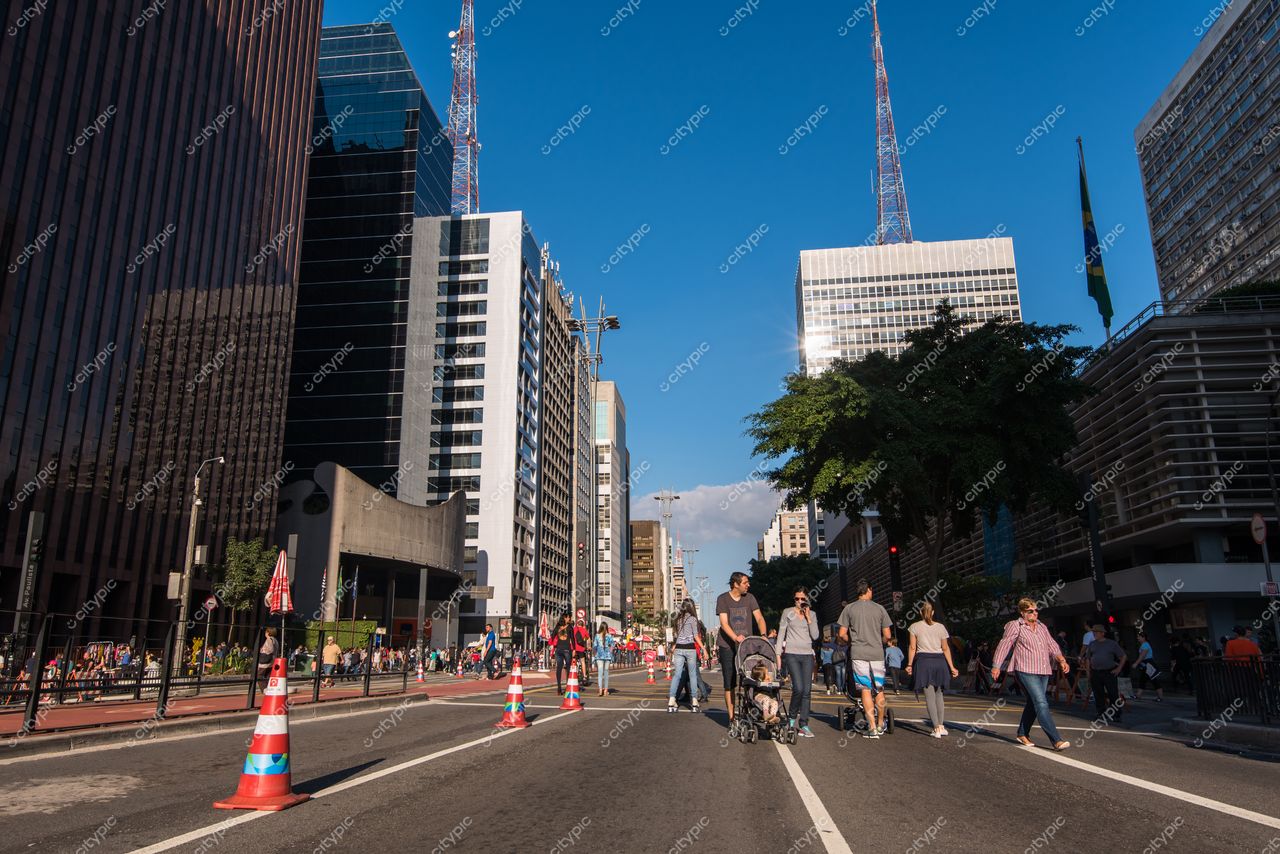 São Paulo, São Paulo, cena movimentada na Avenida Paulista com pessoas e carrinhos de bebê sob céu azul iluminado