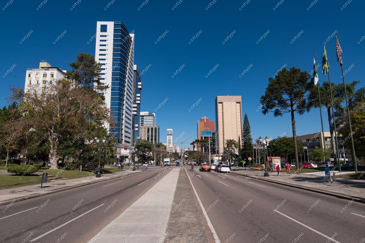 Curitiba, Paraná vista urbana em dia ensolarado com edifícios modernos e vegetação ao longo da avenida ampla