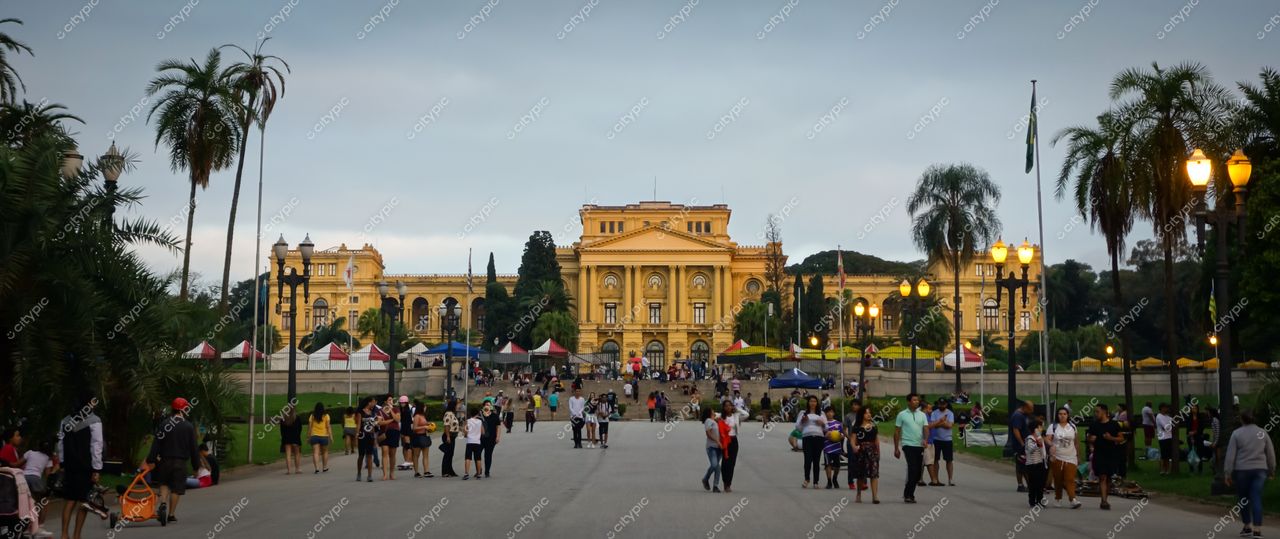 Museu do Ipiranga em São Paulo com fachada neoclássica sob céu cinza e vegetação tropical ao redor
